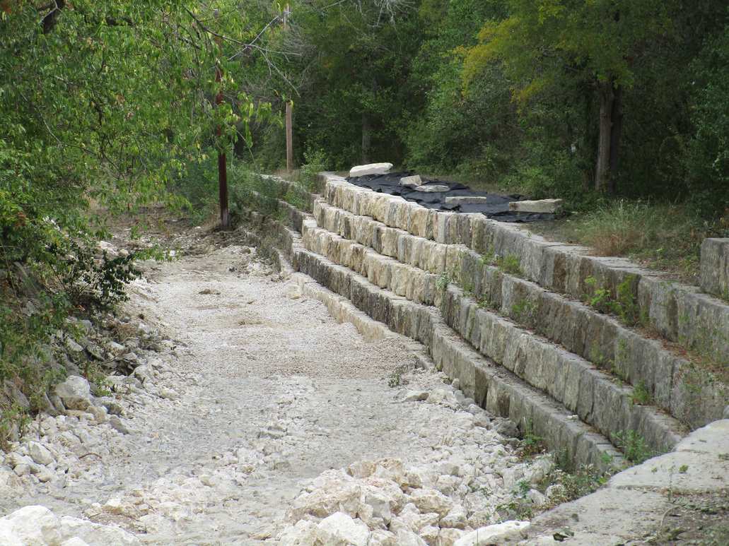a repaired retaining wall and rocks at the bottom of the creek bed